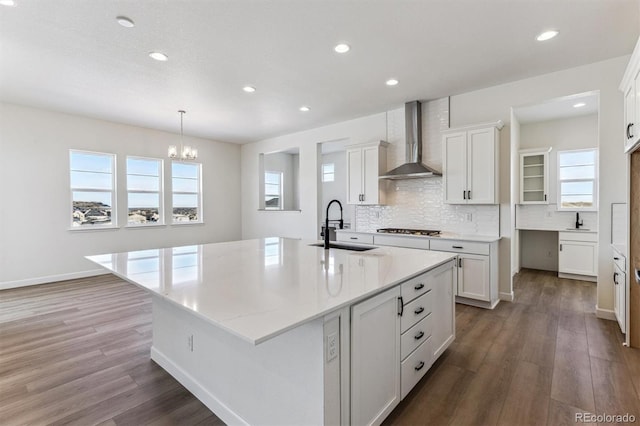 kitchen with a large island, sink, gas cooktop, and wall chimney exhaust hood