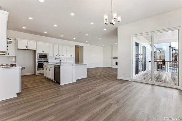 kitchen featuring sink, white cabinetry, hanging light fixtures, appliances with stainless steel finishes, and a kitchen island with sink