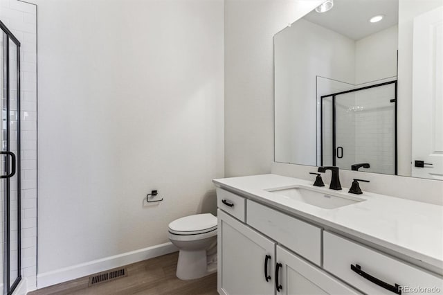 bathroom with vanity, wood-type flooring, a shower with door, and toilet