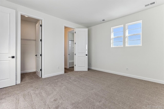 unfurnished bedroom with a walk in closet, carpet flooring, and a closet