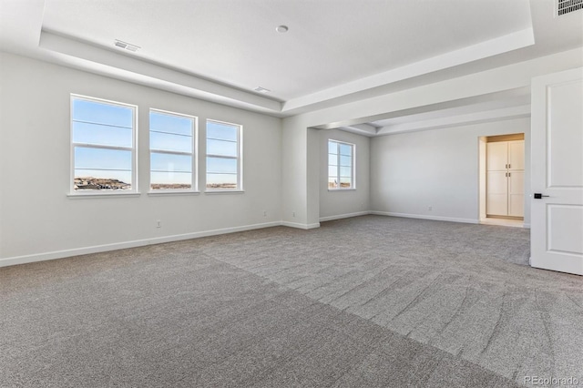 carpeted empty room with a tray ceiling