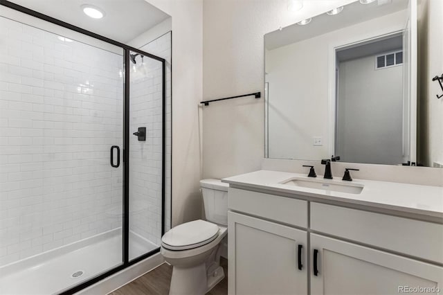 bathroom with vanity, an enclosed shower, hardwood / wood-style flooring, and toilet