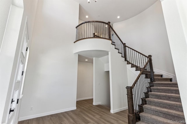 stairway with wood-type flooring and a high ceiling