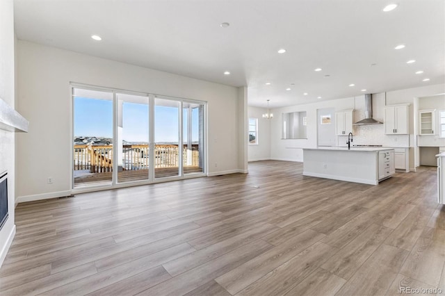 unfurnished living room with a notable chandelier and light wood-type flooring