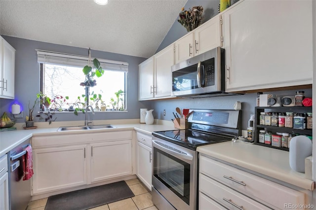 kitchen featuring lofted ceiling, sink, white cabinets, stainless steel appliances, and a textured ceiling