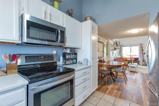 kitchen featuring white cabinetry, light tile patterned floors, a textured ceiling, and appliances with stainless steel finishes