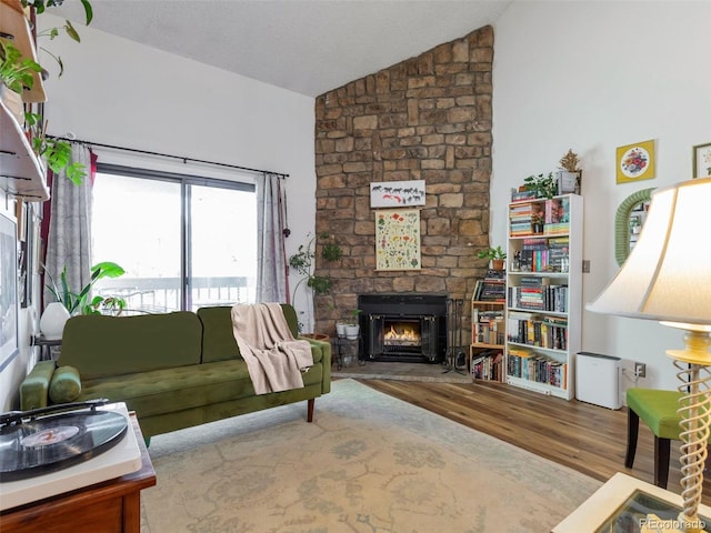 living room with a stone fireplace, vaulted ceiling, and wood-type flooring