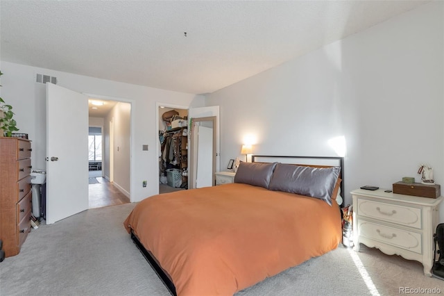 carpeted bedroom featuring a spacious closet and a textured ceiling