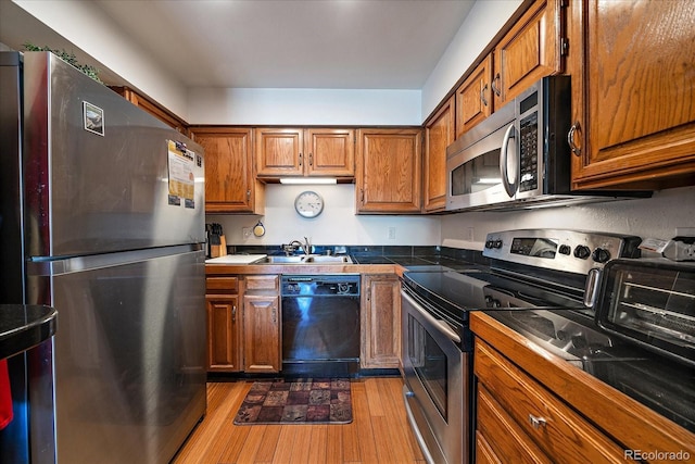 31270 John Wallace Rd Unit 310, Evergreen, CO 80439 - kitchen featuring appliances with stainless steel finishes, a sink, light wood-type flooring, and brown cabinets
