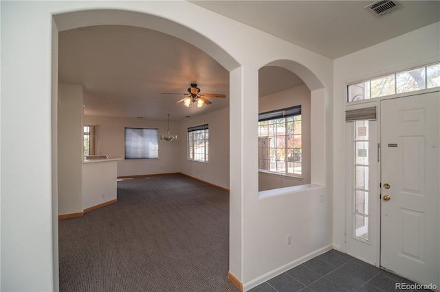 carpeted foyer entrance featuring ceiling fan with notable chandelier