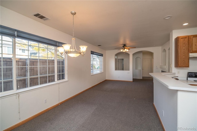 kitchen with ceiling fan with notable chandelier, kitchen peninsula, dark carpet, and hanging light fixtures