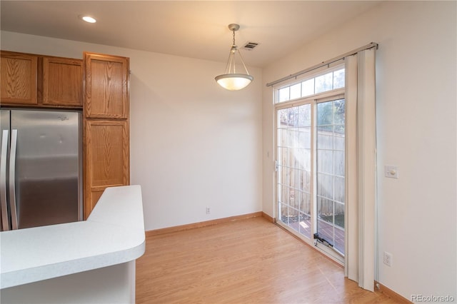 kitchen featuring hanging light fixtures, light hardwood / wood-style floors, and stainless steel refrigerator