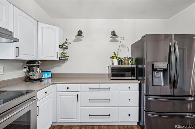 kitchen with white cabinetry, range hood, hardwood / wood-style flooring, and appliances with stainless steel finishes