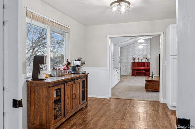 hallway with hardwood / wood-style floors, brick wall, and vaulted ceiling