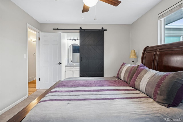 carpeted bedroom with ceiling fan, a barn door, and ensuite bath