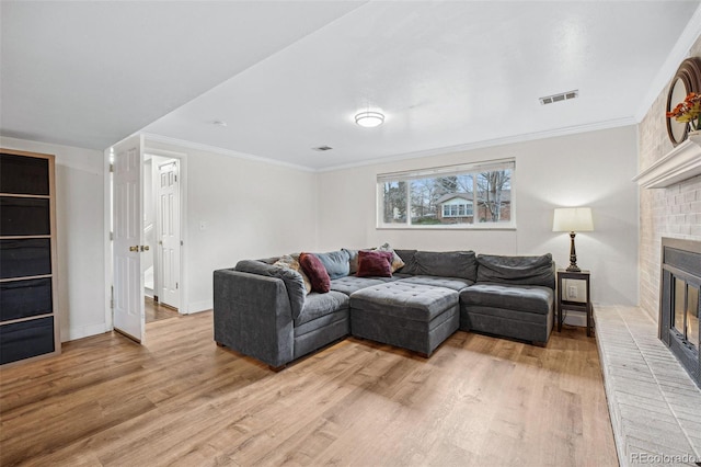 living room featuring light hardwood / wood-style floors, ornamental molding, and a fireplace