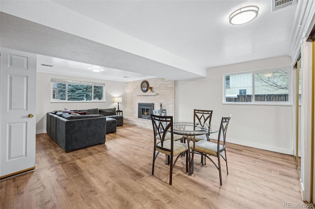 dining room with light wood-type flooring and a brick fireplace