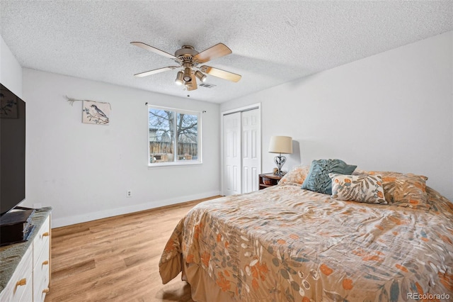 bedroom with ceiling fan, a closet, light hardwood / wood-style floors, and a textured ceiling