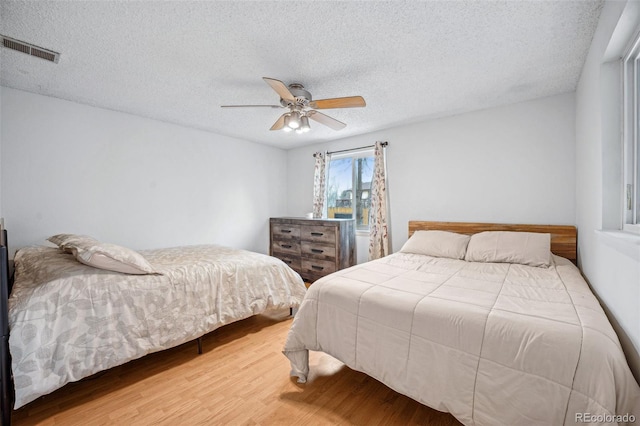 bedroom with a textured ceiling, hardwood / wood-style flooring, and ceiling fan