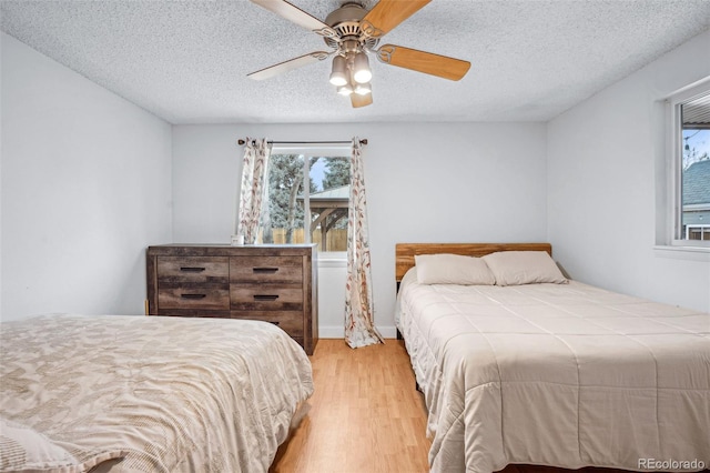 bedroom with ceiling fan, a textured ceiling, and light wood-type flooring