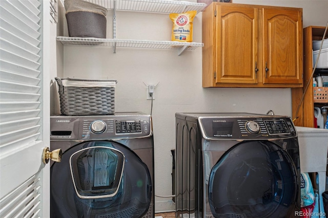 clothes washing area with cabinets and washing machine and clothes dryer