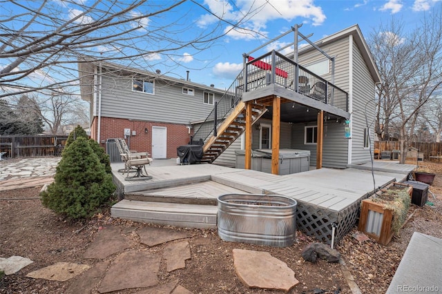 back of house featuring a deck, a patio, and a hot tub