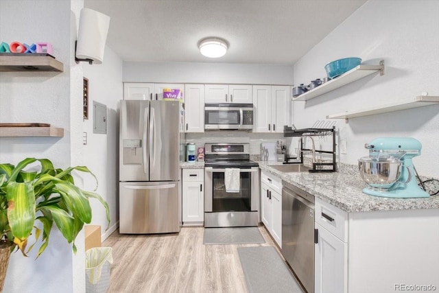 5300 E Cherry Creek S Drive 804, Denver, CO 80246 - kitchen with open shelves, appliances with stainless steel finishes, white cabinets, light wood-style flooring, and light stone countertops