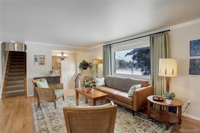 living room with ornamental molding, a notable chandelier, and light hardwood / wood-style flooring