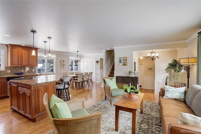 living room featuring crown molding, an inviting chandelier, and light hardwood / wood-style floors