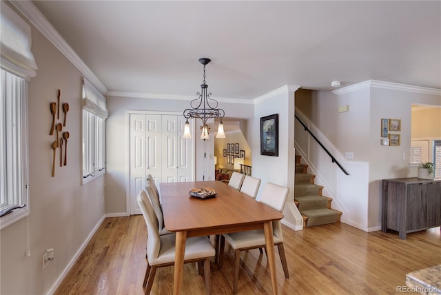 dining space featuring ornamental molding, a chandelier, a wealth of natural light, and light hardwood / wood-style floors