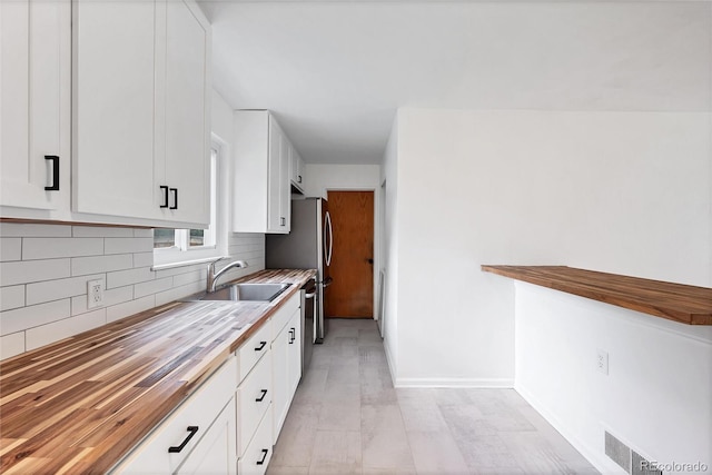 6765 W 33rd Ave, Wheat Ridge, CO 80033 - kitchen with wooden counters, decorative backsplash, white cabinets, and stainless steel dishwasher