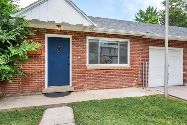 6765 W 33rd Ave, Wheat Ridge, CO 80033 - property entrance featuring brick siding, an attached garage, roof with shingles, and board and batten siding