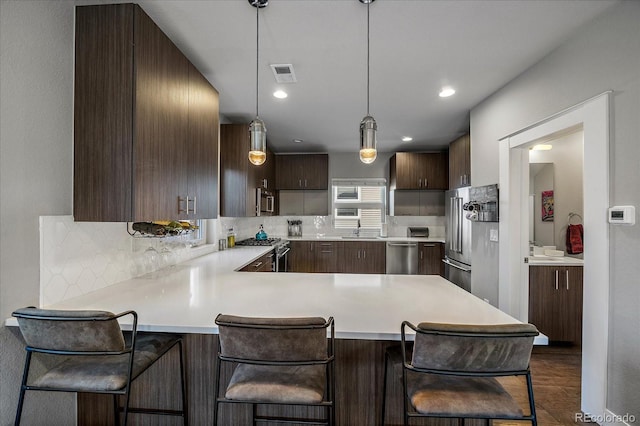 kitchen featuring a kitchen breakfast bar, high quality appliances, kitchen peninsula, and hanging light fixtures