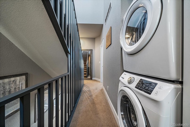 laundry area featuring stacked washing maching and dryer, carpet, baseboards, laundry area, and a textured wall