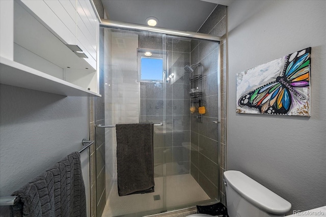 bathroom featuring toilet, a shower stall, and a textured wall