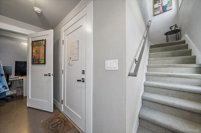 foyer with stairway, dark tile patterned floors, and a textured ceiling