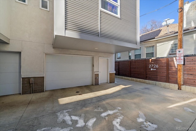 garage featuring driveway and fence