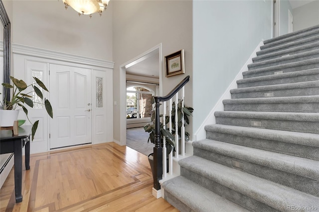7472 S Utica St, Littleton, CO 80128 - entrance foyer featuring stairs, a high ceiling, light wood-style floors, a chandelier, and baseboards