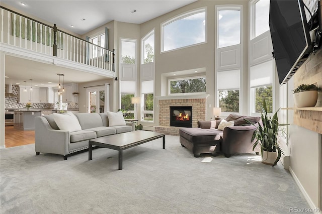 7472 S Utica St, Littleton, CO 80128 - living area featuring light carpet, a high ceiling, a fireplace, baseboards, and recessed lighting