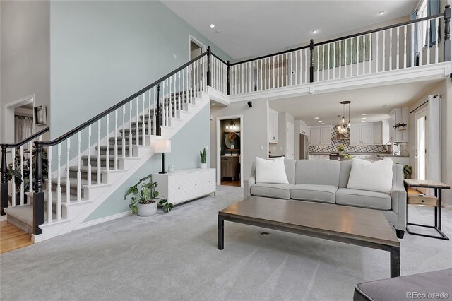 7472 S Utica St, Littleton, CO 80128 - living room featuring a high ceiling, stairs, light carpet, recessed lighting, and a chandelier
