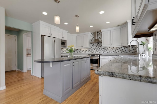 7472 S Utica St, Littleton, CO 80128 - kitchen featuring stainless steel appliances, wall chimney range hood, white cabinetry, backsplash, and light wood-style floors
