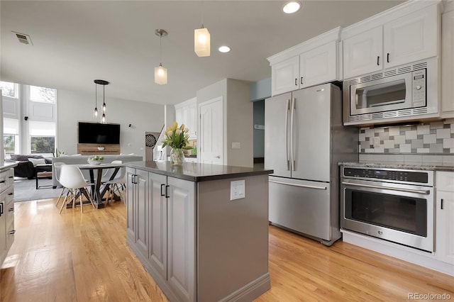 7472 S Utica St, Littleton, CO 80128 - kitchen featuring stainless steel appliances, light wood-type flooring, open floor plan, white cabinets, and tasteful backsplash