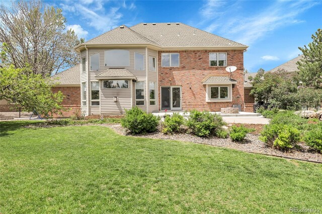 7472 S Utica St, Littleton, CO 80128 - rear view of house featuring a patio, a lawn, brick siding, and a shingled roof