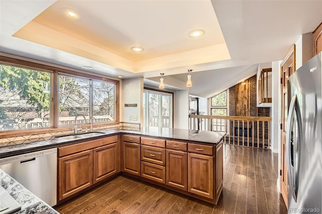8159 Lodgepole Trl, Lone Tree, CO 80124 - kitchen with stainless steel appliances, a sink, a tray ceiling, brown cabinets, and dark wood-type flooring