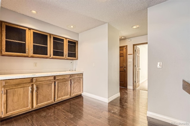 8159 Lodgepole Trl, Lone Tree, CO 80124 - kitchen featuring dark wood-type flooring, baseboards, glass insert cabinets, a sink, and a textured ceiling