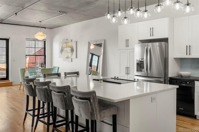 kitchen with black appliances, light wood-type flooring, decorative backsplash, white cabinetry, and a center island