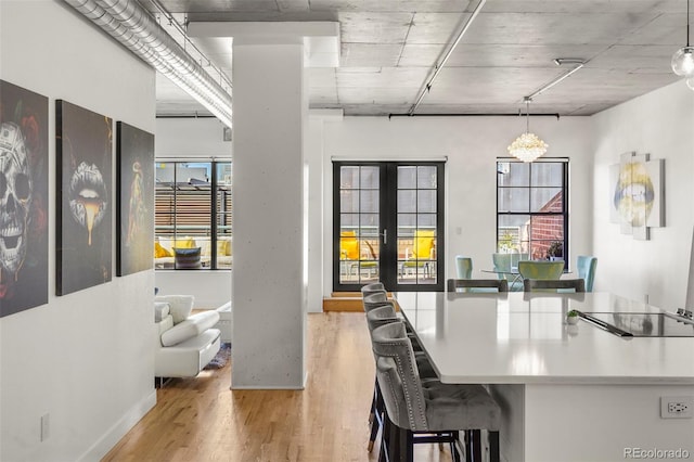 dining space featuring light wood-style floors, plenty of natural light, french doors, and baseboards