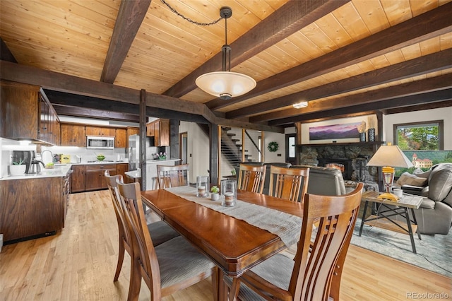 32462 Lodgepole Dr, Evergreen, CO 80439 - dining room with stairs, a wood ceiling with exposed beams, a fireplace, and light wood-style flooring