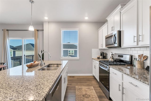 kitchen featuring sink, appliances with stainless steel finishes, white cabinets, pendant lighting, and backsplash