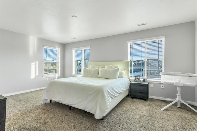 bedroom featuring baseboards, multiple windows, visible vents, and light colored carpet